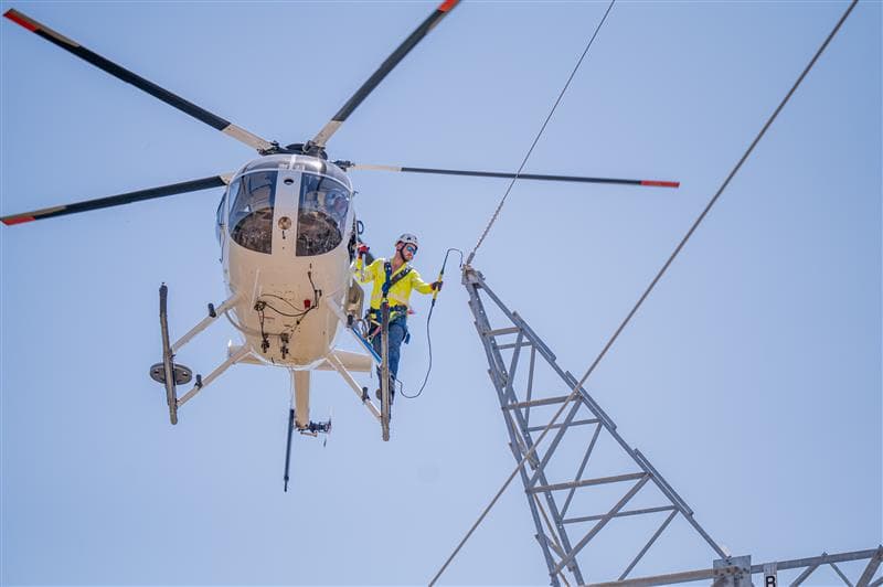 Lineworker repairing a line from a hovering helicopter |